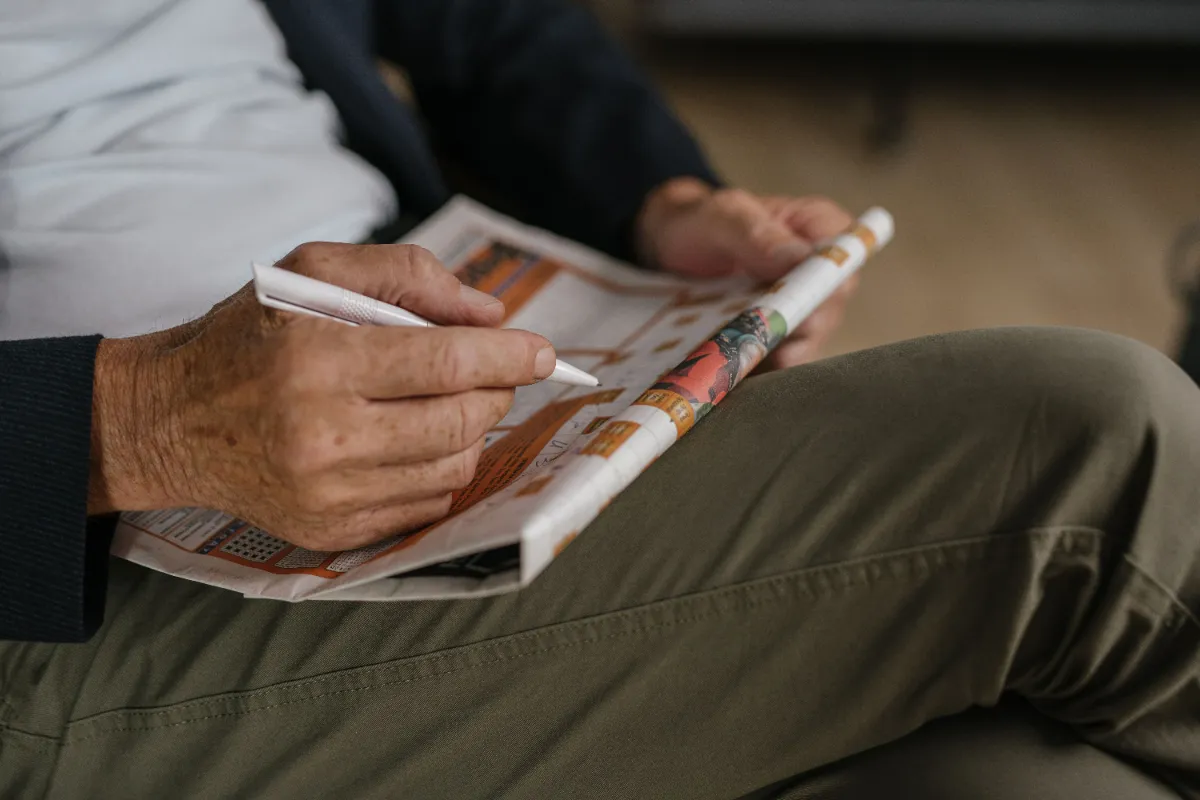 A printed crossword puzzle being solved at a table